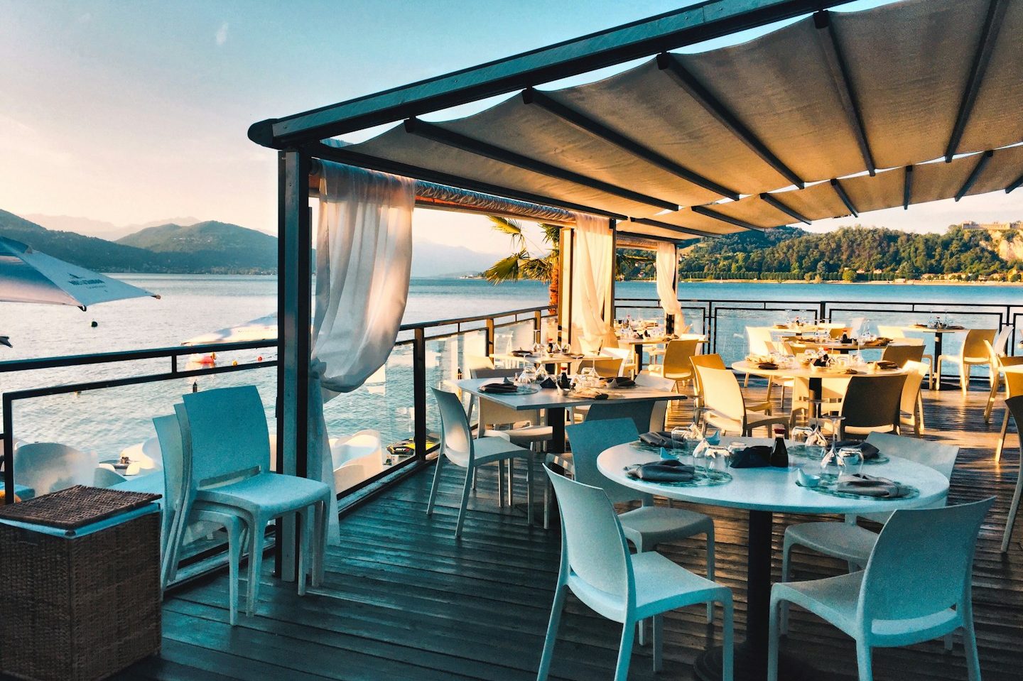 Wine & Dine Tische und Stühle aus Rattan mit Blick auf das blaue Wasser des Meeres.
